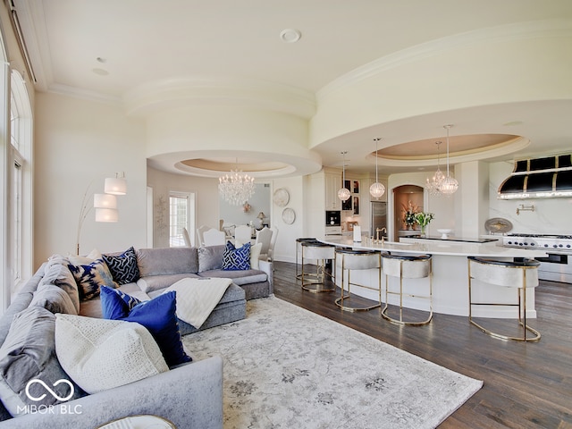 living room featuring crown molding, a tray ceiling, dark wood-type flooring, and a chandelier