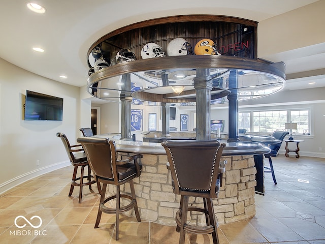 dining room with light tile patterned flooring, bar area, and decorative columns