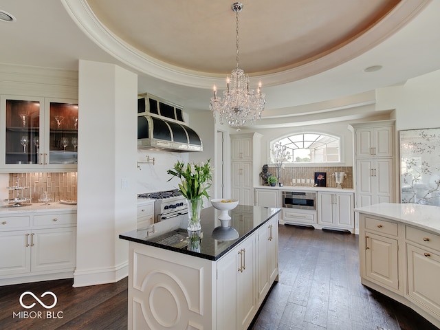 kitchen featuring white cabinetry, appliances with stainless steel finishes, extractor fan, and a tray ceiling