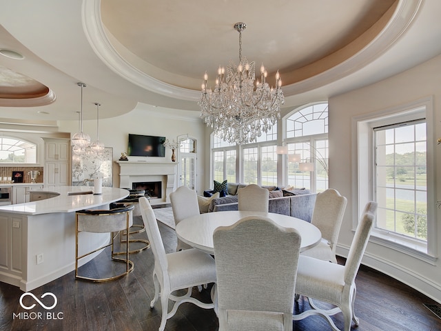 dining area featuring ornamental molding, dark wood-type flooring, a chandelier, and a tray ceiling