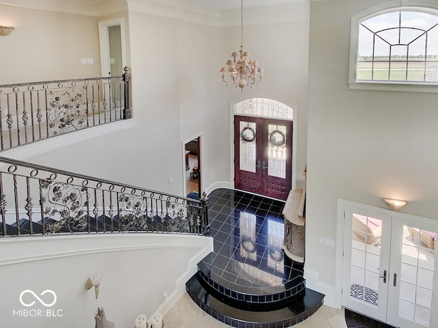 tiled foyer entrance featuring ornamental molding, a chandelier, and french doors