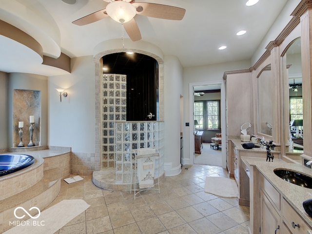 bathroom featuring ceiling fan, vanity, and tiled tub