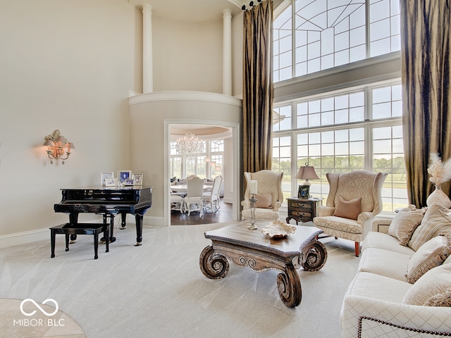 carpeted living room with a towering ceiling and a chandelier