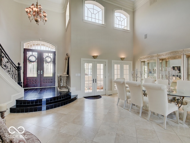 tiled entrance foyer featuring a notable chandelier, ornamental molding, and french doors