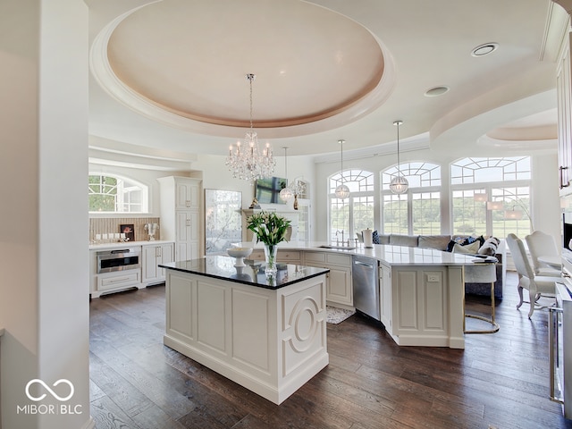 kitchen featuring kitchen peninsula, dishwasher, sink, white cabinets, and a tray ceiling