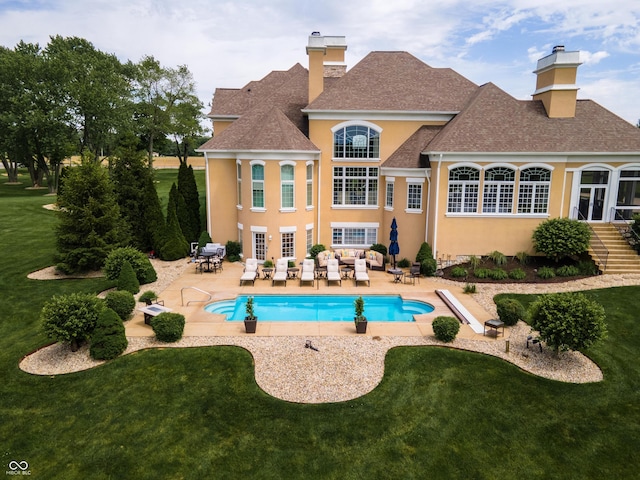 back of property with an outdoor living space, a patio, and a lawn