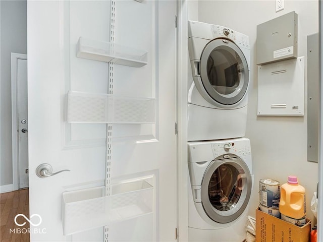 laundry area featuring stacked washing maching and dryer and dark wood-type flooring