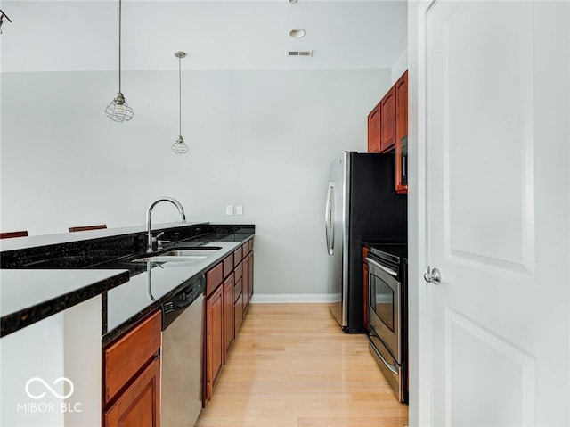 kitchen featuring range, light hardwood / wood-style flooring, dark stone countertops, dishwasher, and pendant lighting