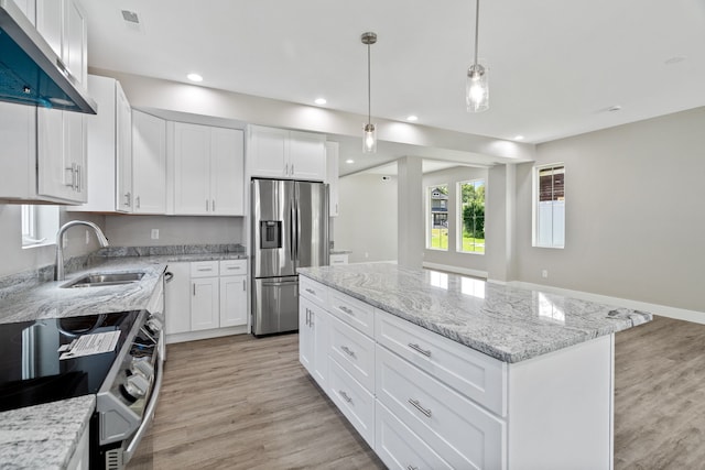 kitchen with appliances with stainless steel finishes, white cabinets, light hardwood / wood-style flooring, a center island, and sink