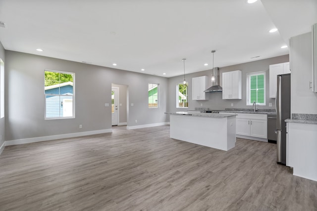 kitchen with a center island, light hardwood / wood-style floors, a wealth of natural light, and wall chimney range hood