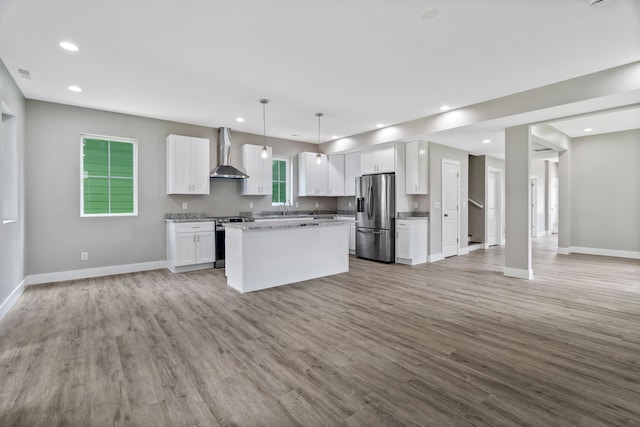 kitchen featuring white cabinets, light hardwood / wood-style flooring, stainless steel appliances, and wall chimney exhaust hood