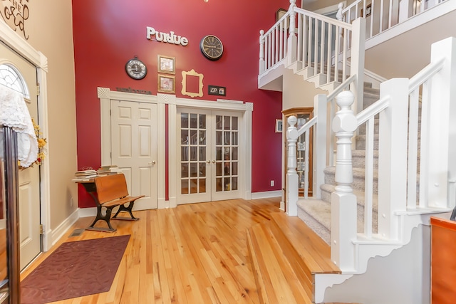 foyer featuring a high ceiling, wood-type flooring, and french doors