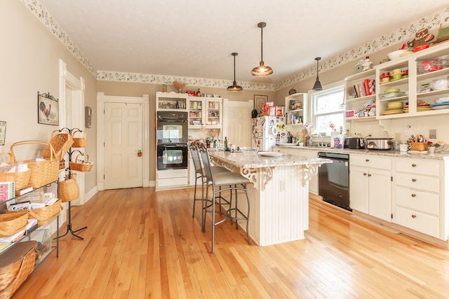 kitchen featuring black appliances, a kitchen island, hanging light fixtures, and light hardwood / wood-style flooring