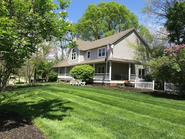 rear view of property featuring a porch and a lawn