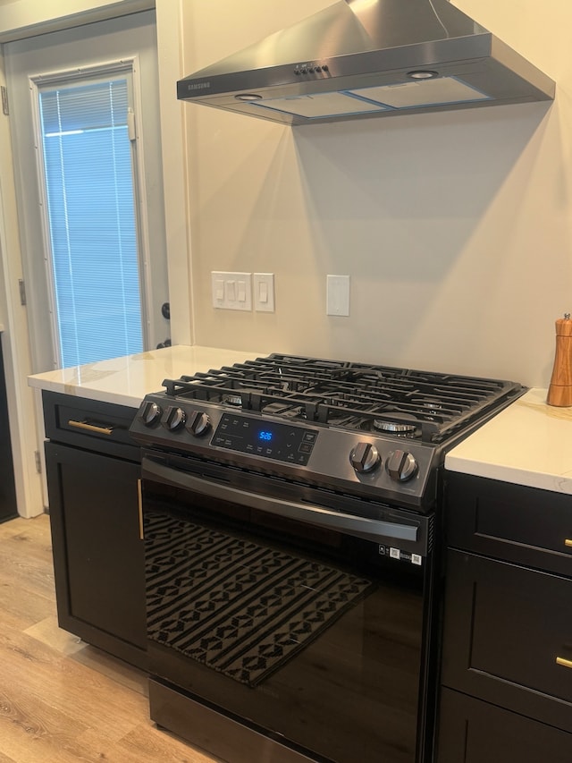 kitchen featuring light hardwood / wood-style flooring, gas stove, and wall chimney exhaust hood