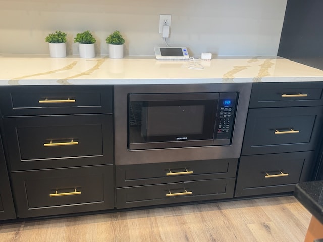 details featuring stainless steel microwave and light hardwood / wood-style floors