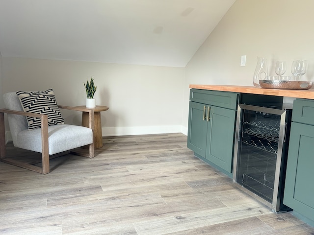 sitting room featuring bar, light wood-type flooring, wine cooler, and vaulted ceiling