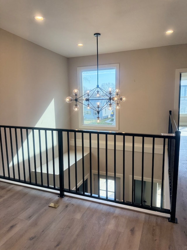 stairs with wood-type flooring, a notable chandelier, and plenty of natural light