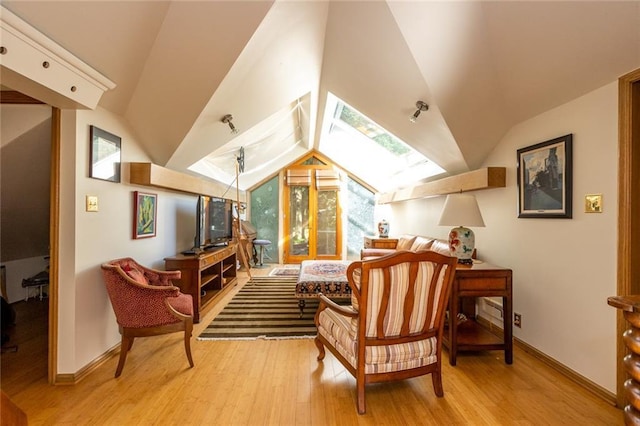 sitting room with vaulted ceiling with skylight and light hardwood / wood-style flooring