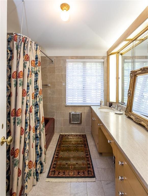 bathroom featuring tile walls, vanity, shower / bathtub combination with curtain, and tile flooring