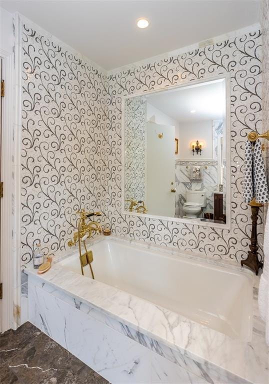 bathroom with toilet and tiled tub