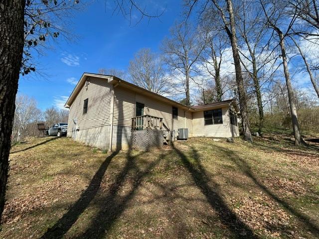 back of house featuring a lawn and cooling unit