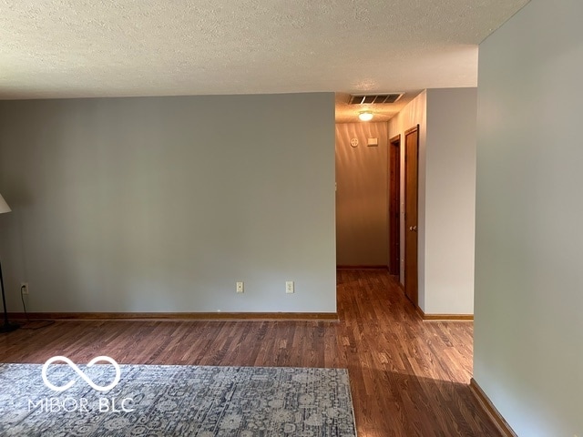 unfurnished room with dark hardwood / wood-style floors and a textured ceiling