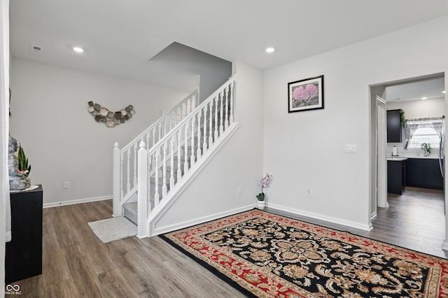 staircase with wood finished floors, baseboards, and recessed lighting