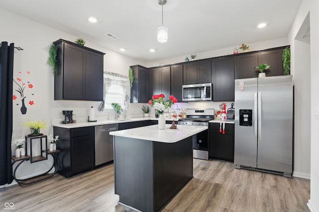 kitchen featuring stainless steel appliances, light wood finished floors, light countertops, decorative light fixtures, and recessed lighting