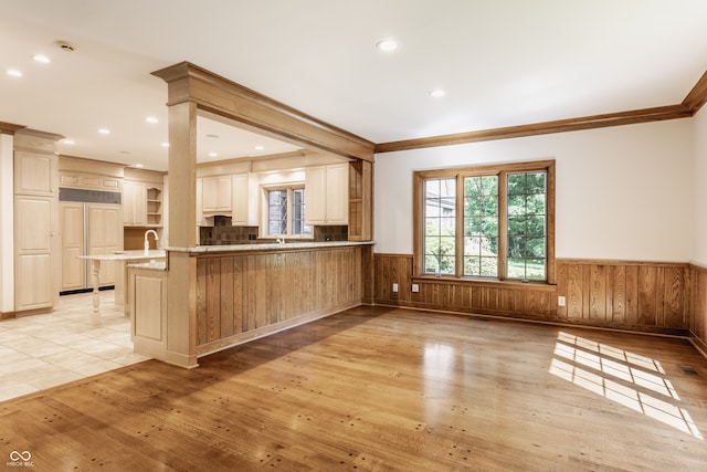 kitchen featuring kitchen peninsula, decorative backsplash, light hardwood / wood-style floors, and ornamental molding