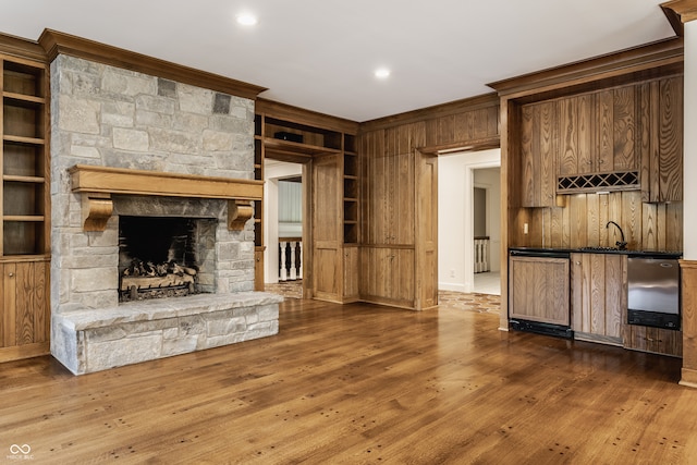 unfurnished living room featuring hardwood / wood-style floors, crown molding, built in features, and a fireplace