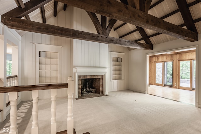 unfurnished living room featuring a fireplace, beam ceiling, light carpet, and plenty of natural light