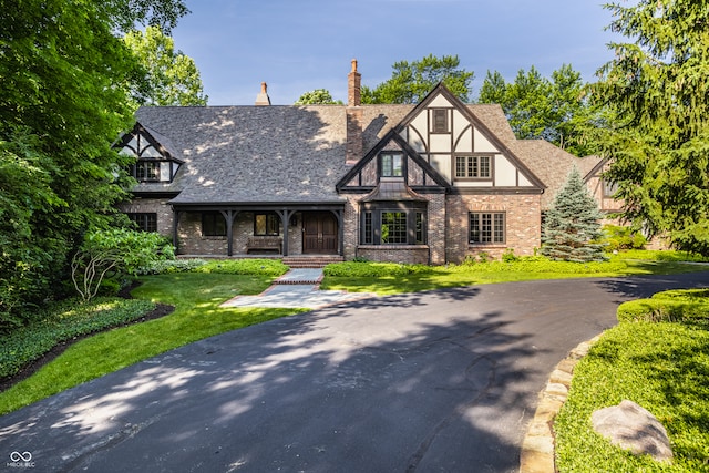 tudor-style house featuring a front lawn