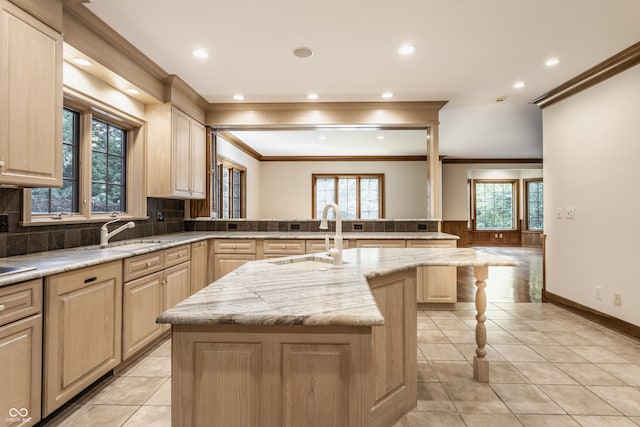 kitchen with plenty of natural light, sink, an island with sink, and light brown cabinetry