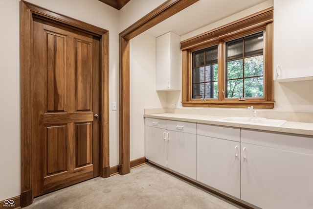 kitchen featuring light colored carpet, white cabinetry, and sink