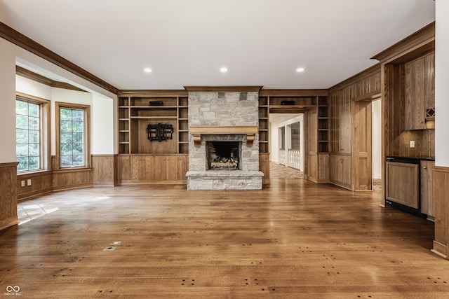 unfurnished living room featuring a fireplace, ornamental molding, dark wood-type flooring, and built in shelves