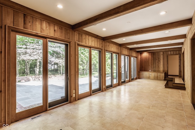 interior space featuring beam ceiling and wood walls