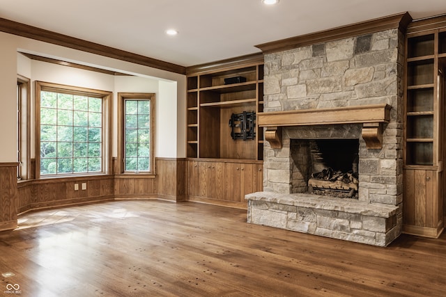 unfurnished living room with a stone fireplace, crown molding, and hardwood / wood-style flooring