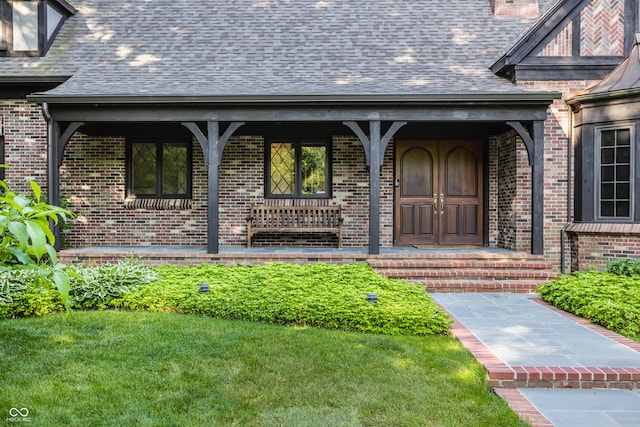 entrance to property featuring covered porch and a yard