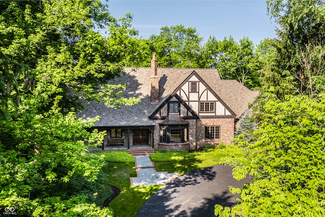 tudor home featuring a front lawn and covered porch