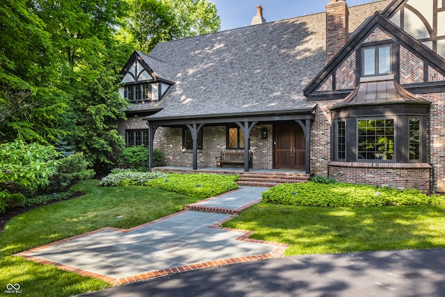 tudor-style house featuring a front yard and a porch