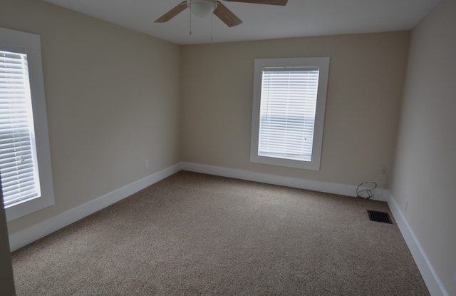 spare room with ceiling fan, a wealth of natural light, and light carpet