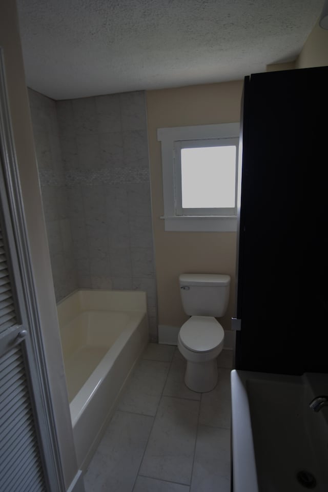 bathroom with a textured ceiling, tile floors, and toilet