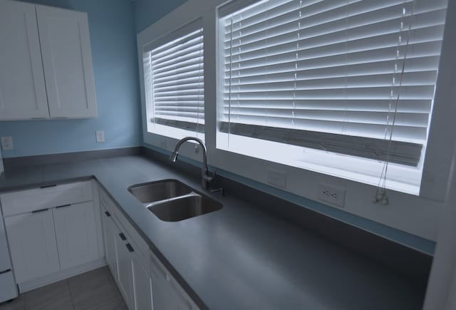 kitchen with tile flooring, white cabinets, and sink