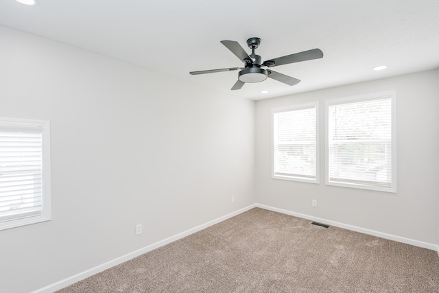 carpeted spare room with ceiling fan and plenty of natural light