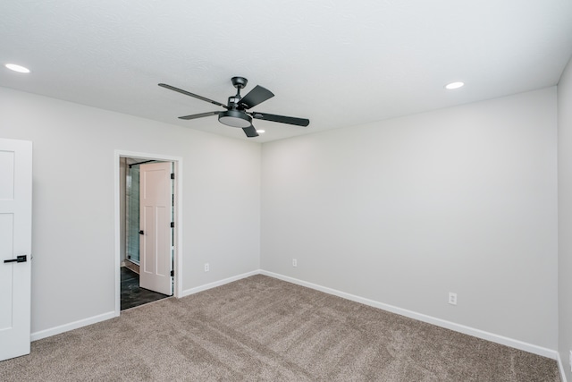 spare room with dark colored carpet and ceiling fan