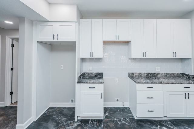 kitchen featuring tasteful backsplash, dark stone countertops, and white cabinets