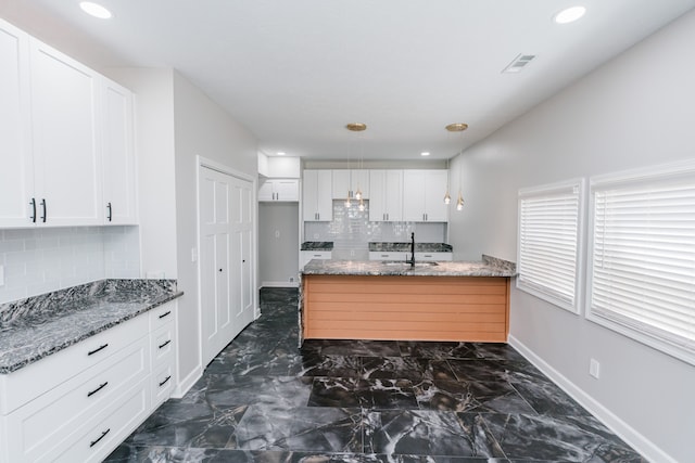 kitchen featuring white cabinetry, sink, backsplash, and stone countertops