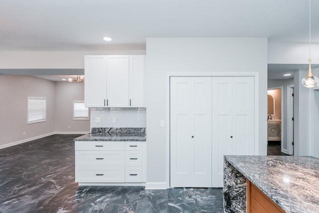 kitchen with backsplash, dark stone counters, decorative light fixtures, and white cabinets