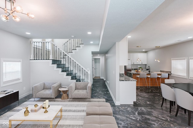 living room featuring an inviting chandelier, sink, and a textured ceiling